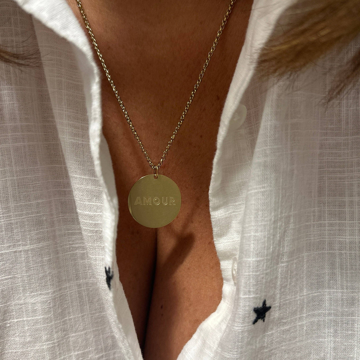 The Amour Necklace from AB Paris features a round golden pendant inscribed with "Amour," symbolizing love and affection.