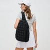 Sol and Selene Quilted Puffer Sling Backpack in black nylon with quilted design, adjustable strap, and zippered compartments.