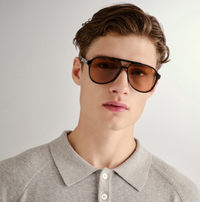 Oversized 70s-inspired aviator sunglasses in classic black with tan-tinted lenses, featuring pyramid stud hardware and a durable, impact-resistant frame.